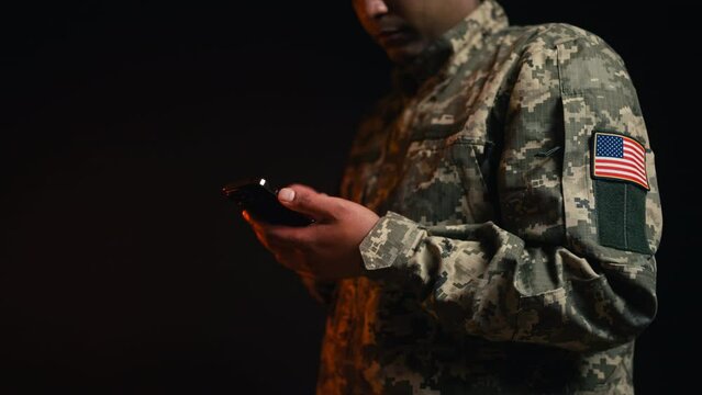 Close-up of soldier with American flag patch scrolling phone, apps for military