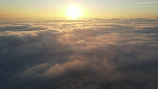 Aerial shot of the sunrise above a layer of clouds
