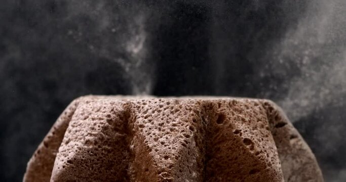 Super slow motion macro of falling white powdered sugar dust particles on Italian culture christmas holidays artisan homemade baked Pandoro cake isolated on black background at 1000 fps.