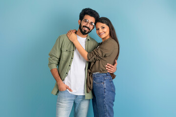 Beautiful millennial indian couple posing on blue studio background