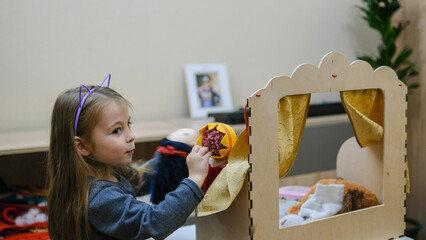 Lovely small girl with doll puppets on her hands, smiling and playing