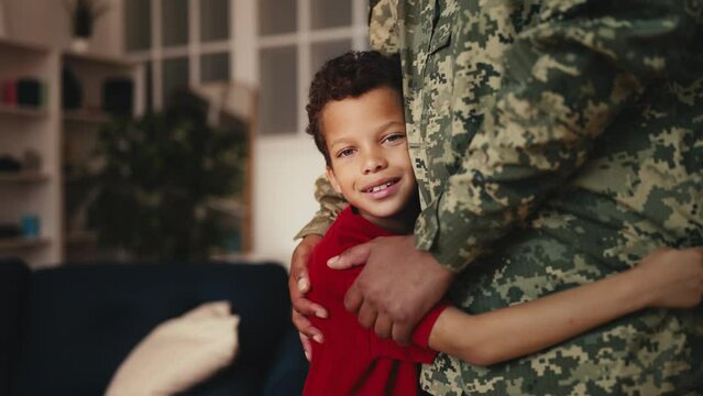 Boy hugging dad in military uniform and smiling, greeting father's comeback