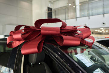 The new car is wrapped in a red bow. Beautiful gift concept.