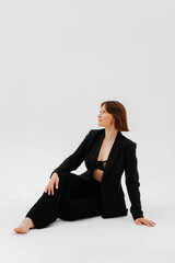 Adult woman in suit and bra posing against white background, studio shot