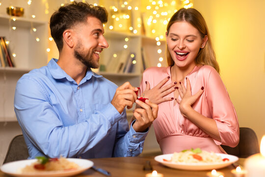 Surprised woman receiving a ring from man during romantic dinner