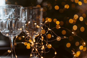 Champagne glasses, New Year decor. New Year's festive setting, family holidays.Two glasses of champagne are on the table against the background of New Year's decorated tree.