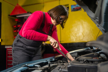 woman auto mechanic repairs car in her workshop small business