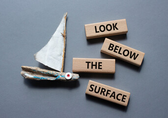 Look below the surface symbol. Concept word Look below the surface on wooden blocks. Beautiful grey...