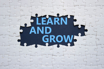 Learn and grow symbol. Concept words Learn and grow on white puzzle. Beautiful deep blue background. Business and Learn and grow concept. Copy space.