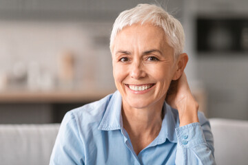 Fototapeta na wymiar Portrait of cheerful mature woman with gray short hair indoor