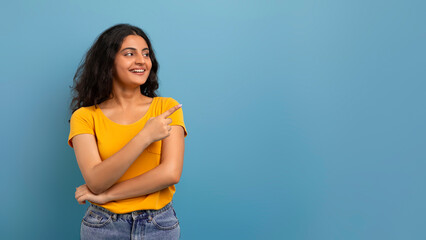 Cheerful young indian woman looking and pointing aside