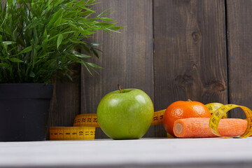 fruits with measuring tape on wooden background