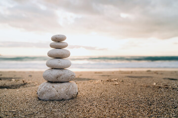 Fototapeta na wymiar A cairn of smooth stones stacked on the sand symbolizes balance and tranquility by the sea