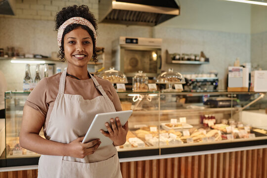 Young african american bakery worker standing against counter joyfully looking at camera