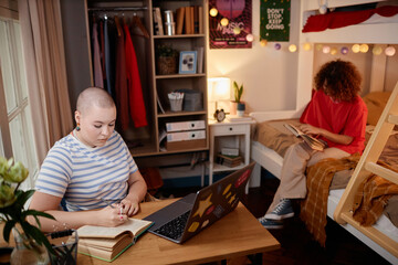 Fototapeta na wymiar Portrait of two young women studying and doing homework in college dorm room, copy space