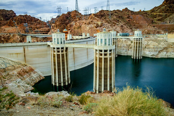 People walk across Hoover Dam with water intakes in the foreground - 691649233