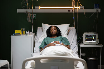 Relieved African female patient on hospital bed in ward recovers wearing oxygen tube in nose.