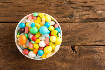 Various kinds of colourful candies in bowl on wooden table. Close up