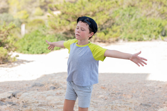 Clam boy standing with outstretched arms in nature and enjoying weather