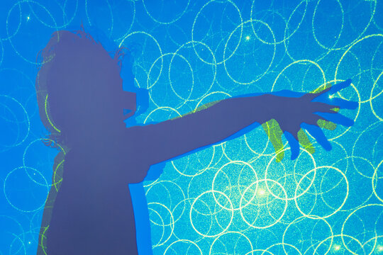 Shadow of unrecognizable kid in 3D glasses enjoying in blue neon studio