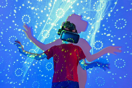 Boy in VR goggles exploring virtual reality in blue neon lights