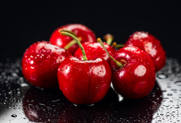 Cherries on black background. Fresh ripe Cherry berries close-up. Heap of Organic red cherries with water drops on grey background. Juicy organic Berries, vegan food.