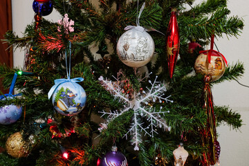 Festive christmas background. Multi-colored lights and balls on the branches of spruce. Blurry lights at night. Decorated Christmas tree on blurred background.