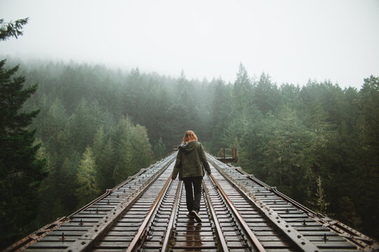 Woman walking in misty forest railroad on Vancouver Island