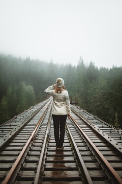Back view of solitary woman in journey on a foggy Vancouver Island train track