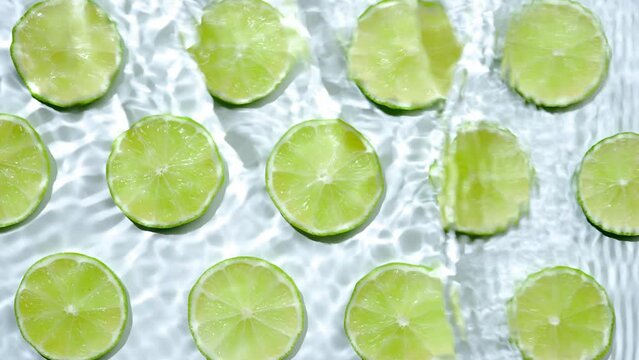 Slice of lime underwater or in water with splashing and droplet top view flat lay on white background.