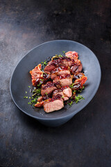Traditional fried wild hare back filet with plums, cranberries and bacon in red wine jus served as close-up on Nordic design plate