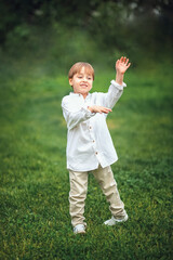 A young handsome boy of European appearance enjoys spending time on the green lawn at home. It's a great time to relax.