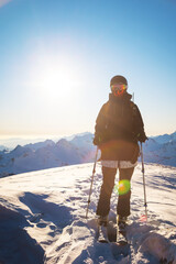 happy woman in a ski suit and helmet stands in the mountains against the backdrop of a mountain...