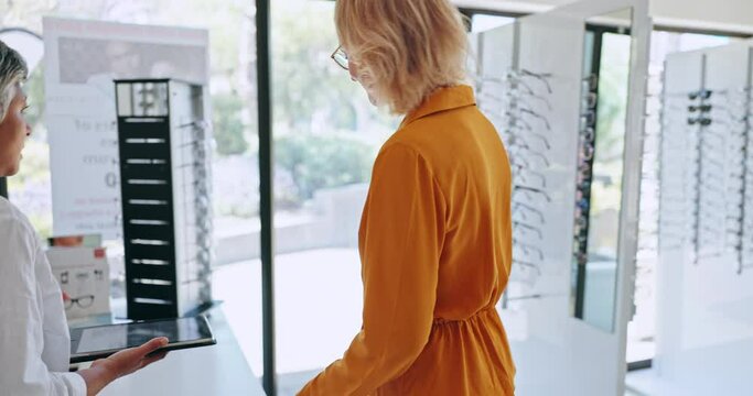 Tablet, optometry and a senior woman with a customer in an eyewear store for consulting or advice. Glasses, appointment or examination with an expert optician and client meeting to improve vision
