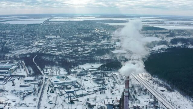Smoking chimney on the background of the city in winter. Environmental pollution from emissions into the atmosphere. Aerial view of atmospheric emissions. Ukraine 2022, the city of Shostka.