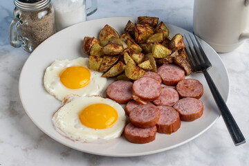 breakfast plate of  fried eggs and kielbasa with home fries - obrazy, fototapety, plakaty