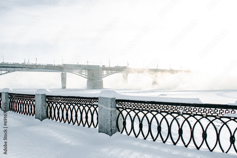 Wall mural bridge is over frozen river. embankment of the ob river in winter in novosibirsk frost day -40 degre