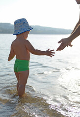 Happy little boy in the sea reaches out to his father.Father and son at the beach.Happy lifestyle childhood concept - 691680017