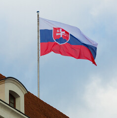 Image of national flag of slovakia waving against blue sky at roof