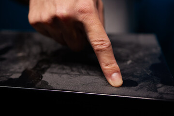 caucasian hand with dust on finger tips after touching black dusty surface, closeup with selective...