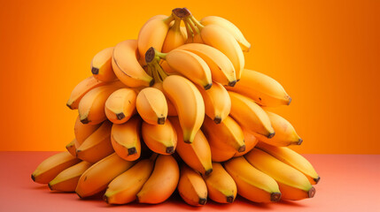 A pile of bunches of large, ripe yellow bananas against an unusual background of rich yellow and pink. Fruits all year round, nutrition and health, vegetarianism