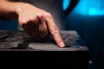 caucasian hand with dust on finger tips after touching black dusty surface, closeup with selective...