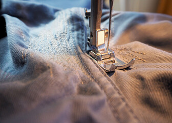 the process of repairing denim trousers on a sewing machine. applying a large number of stitches to...