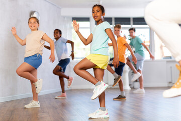 Energetic sporty african american tween girl practicing modern vigorous movements in group dance...