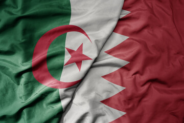 big waving national colorful flag of bahrain and national flag of algeria .