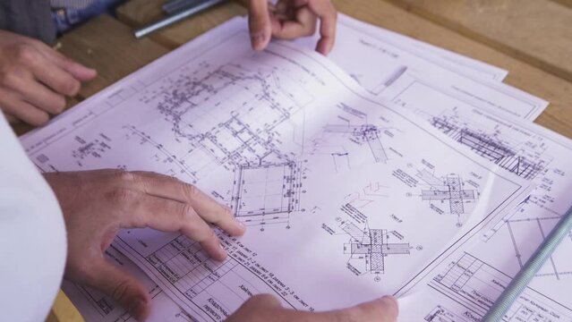 Close up for hands of workers at a factory looking through technical drawings. Blueprints with sketches of projects, engineering concept.