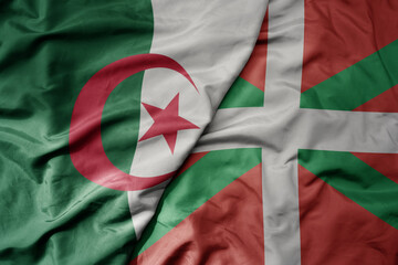 big waving national colorful flag of basque country and national flag of algeria .