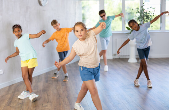 Group of preteenagers in casual clothes training hip-hop in class, learning modern dance movements. High quality photo