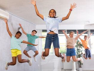 African male boy engaged shake leg in fitness studio with friends, group of youthful children...