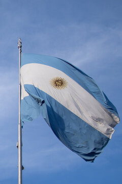 Bandera argentina flameando en mastil, delante de un cielo azul